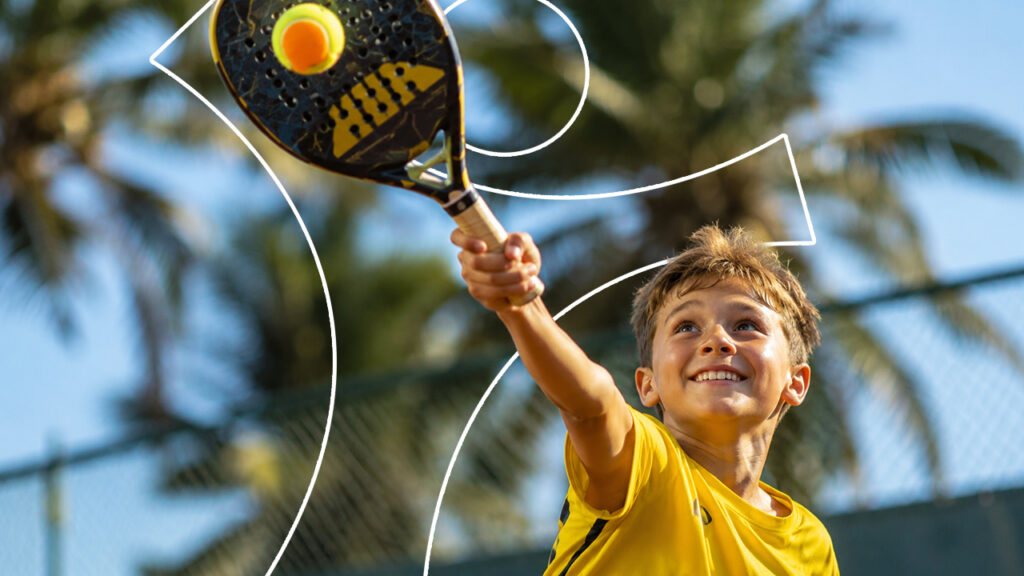 Crianças sorrindo e correndo na areia com raquetes durante a aula de beach tennis infantil em Jundiaí na estrutura da VtennisTeam.