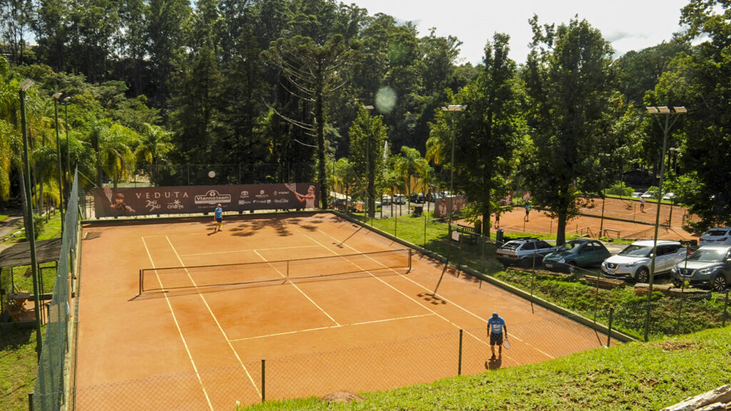 Visão ampla da excelente e moderna quadra de tênis em Jundiaí da VtennisTeam, cercada por natureza e preparada para treinos profissionais.